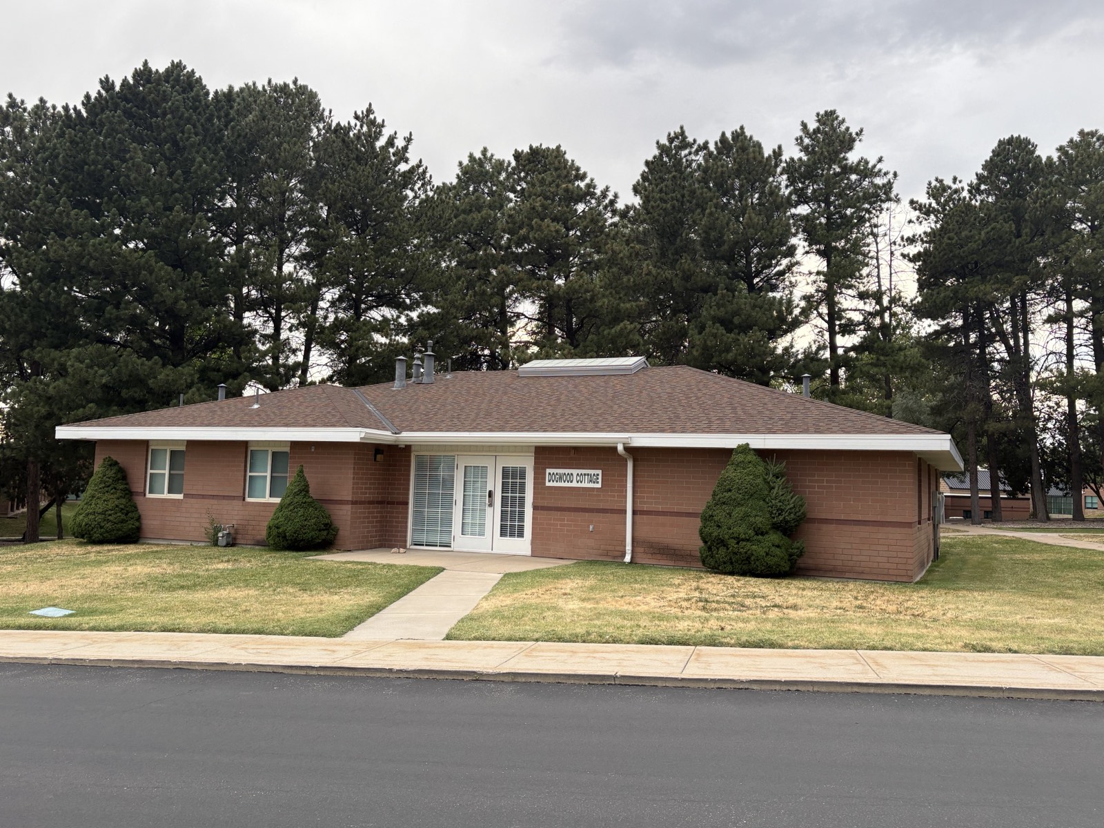Dogwood Cottage, a single-story brick residential cottage at the Ogden campus surrounded by pines